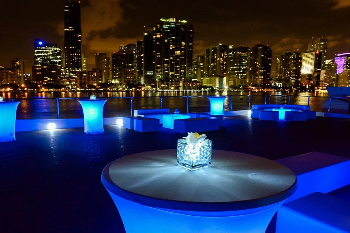 An intimate yacht lounge with blue lighting and views of Manhattan